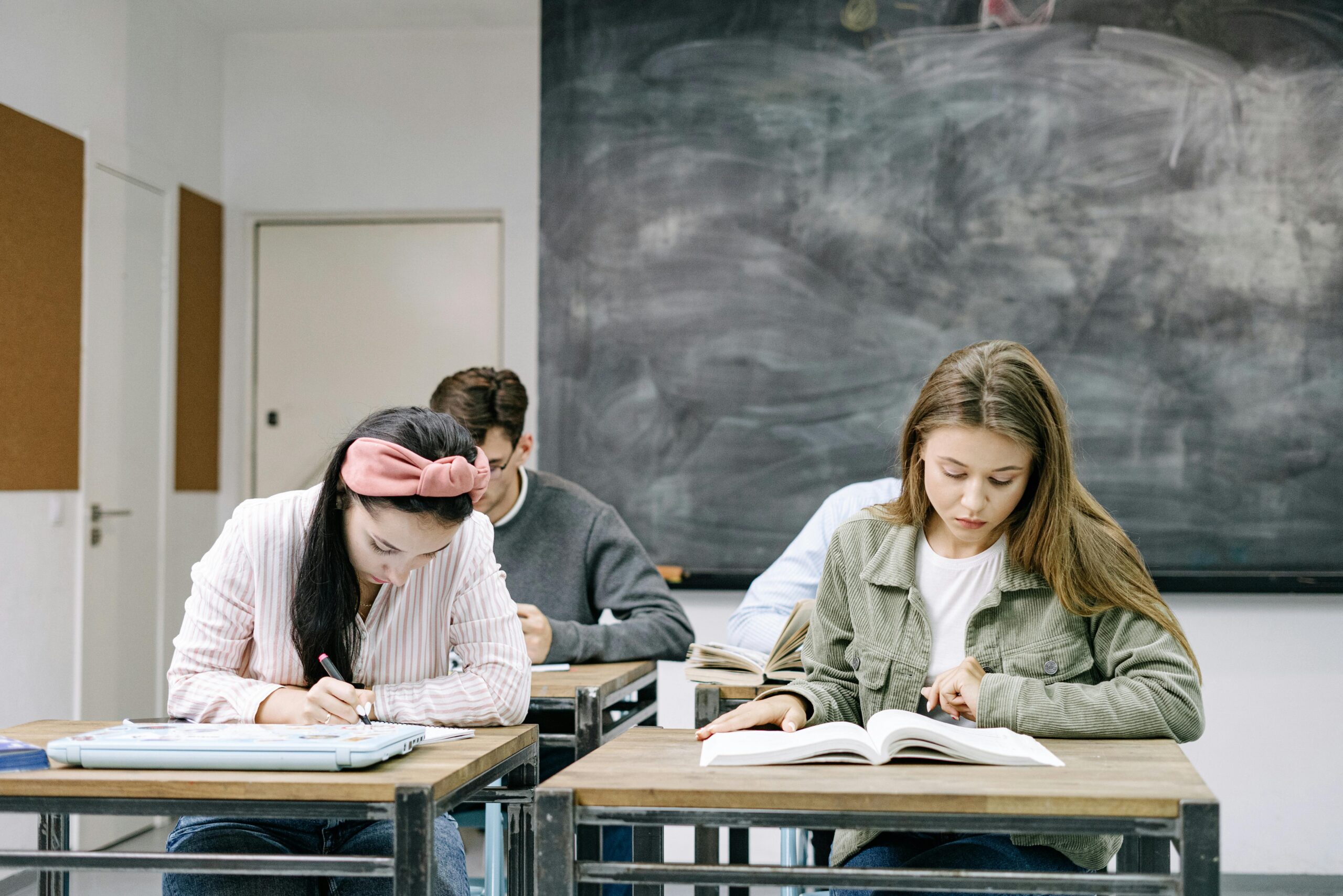 Young students studying in a classroom, focused on reading and writing assignments.